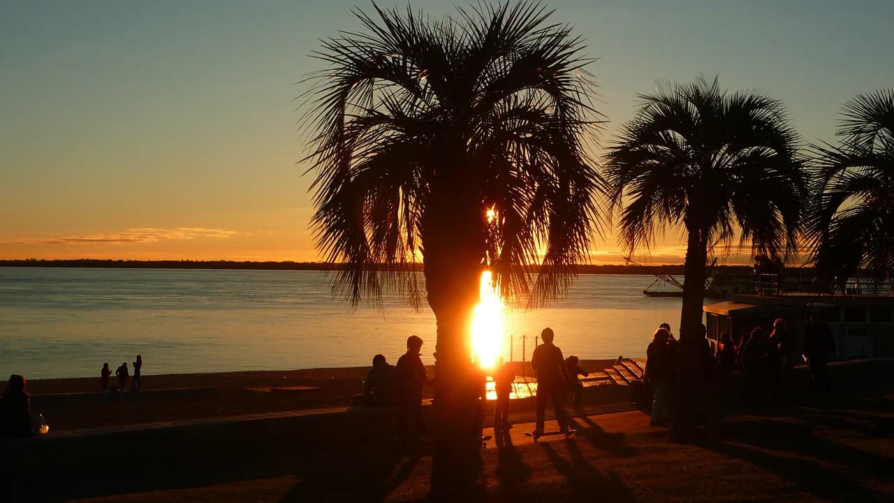 Atardecer en la costanera de Corrientes sobre el río Paraná, con palmeras