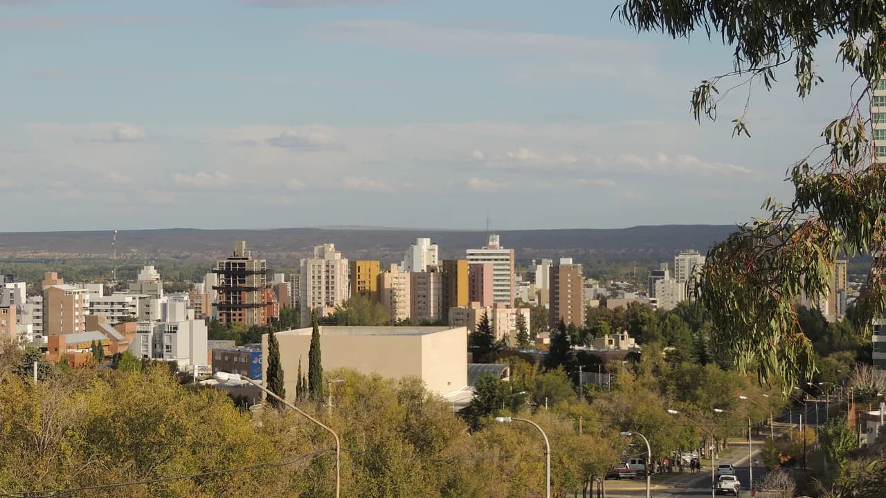 Skyline de Neuquén capital, edificios bajos y árboles patagónicos